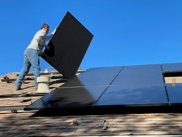 Installer placing a solar panel on a roof